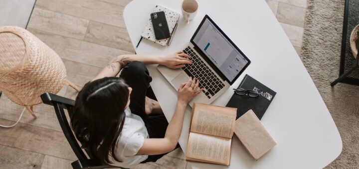 young lady typing on keyboard of laptop in living room